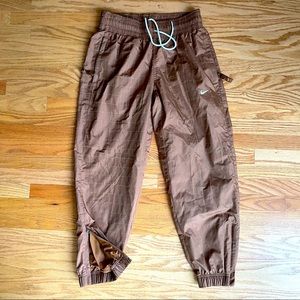 Chestnut brown Nike trackpants with reflective trim woven in fabric.